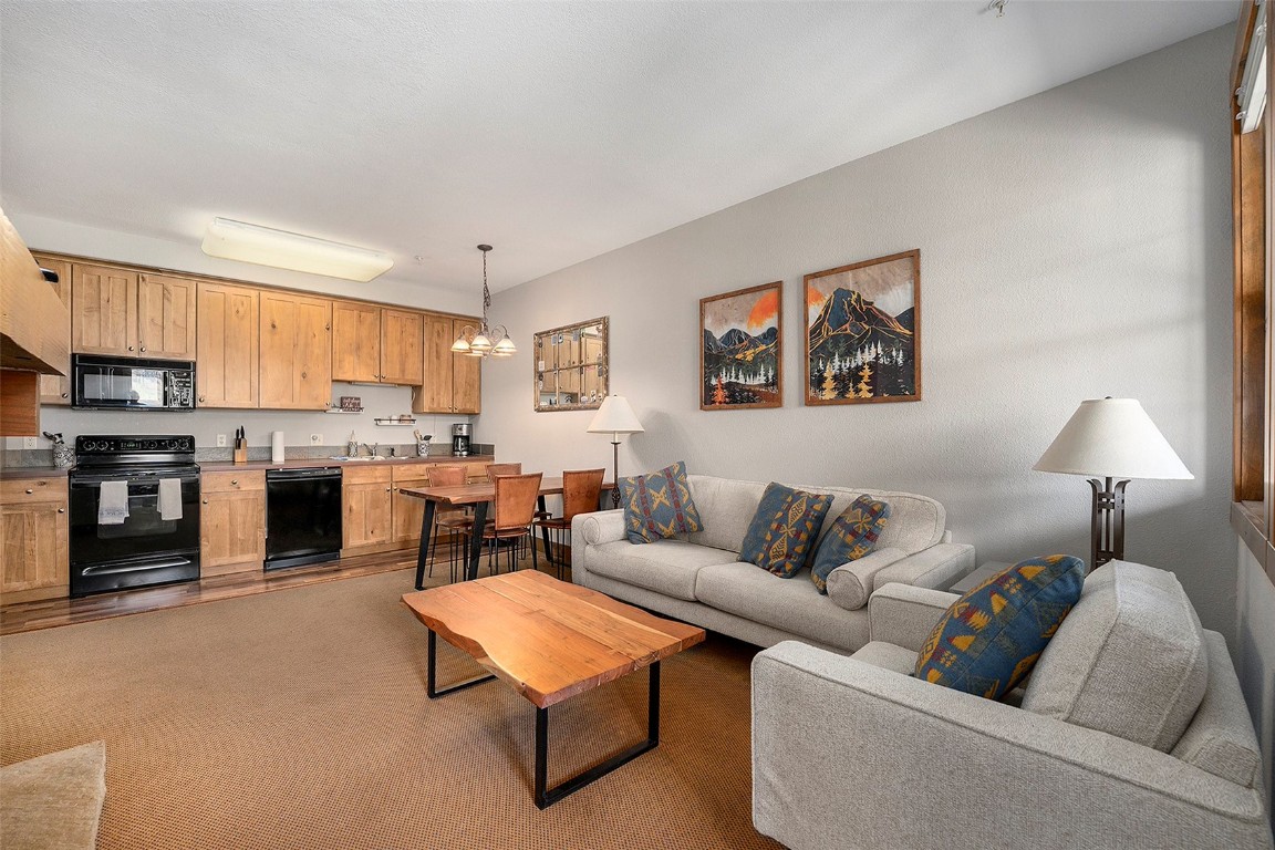 Carpeted living room with a notable chandelier