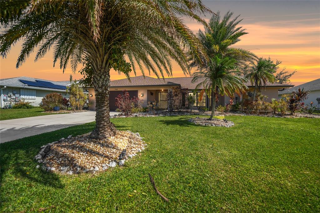 a front view of a house with a yard and palm tree