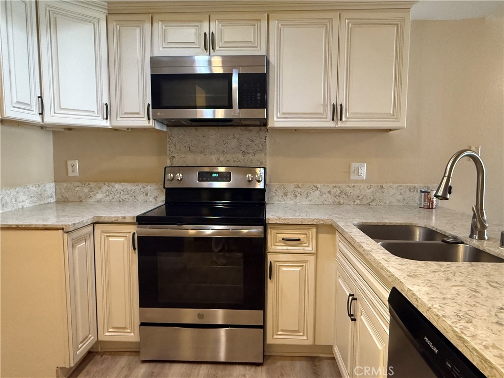 a kitchen with granite countertop a stove a microwave a sink and cabinets