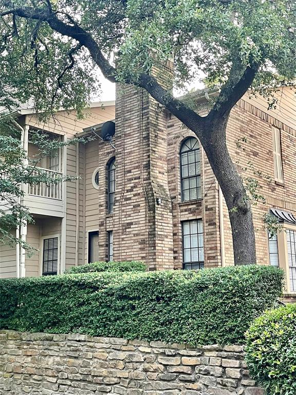 a view of a brick house with a large windows and large trees