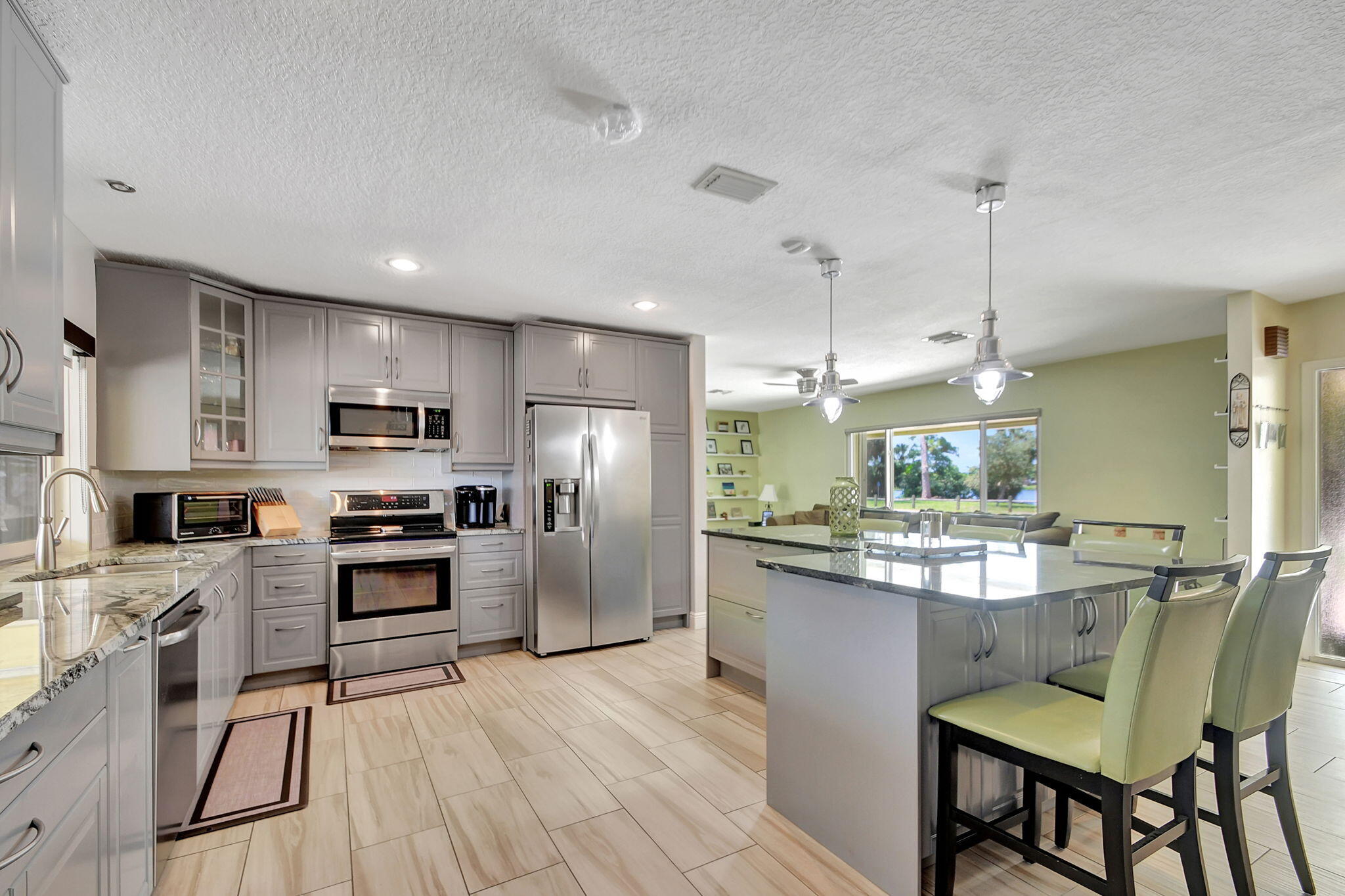 a kitchen with stainless steel appliances kitchen island granite countertop a refrigerator a stove top oven a sink dishwasher and white cabinets with wooden floor