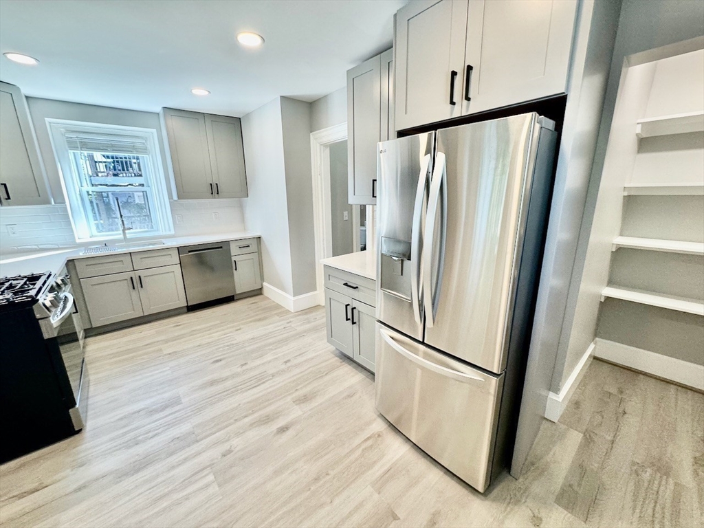 a kitchen with stainless steel appliances a refrigerator sink and wooden floor