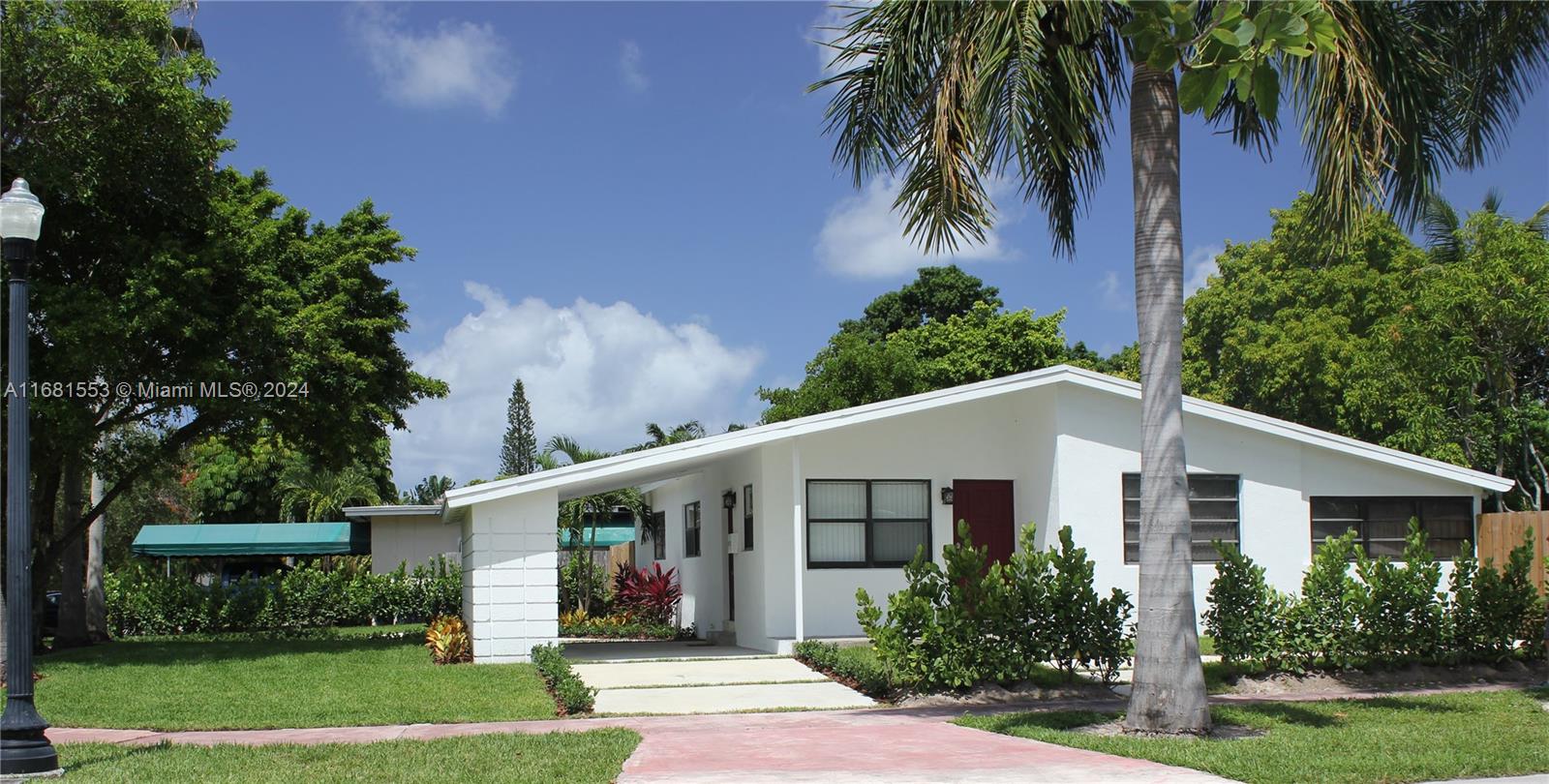 a view of a white house next to a yard with palm trees