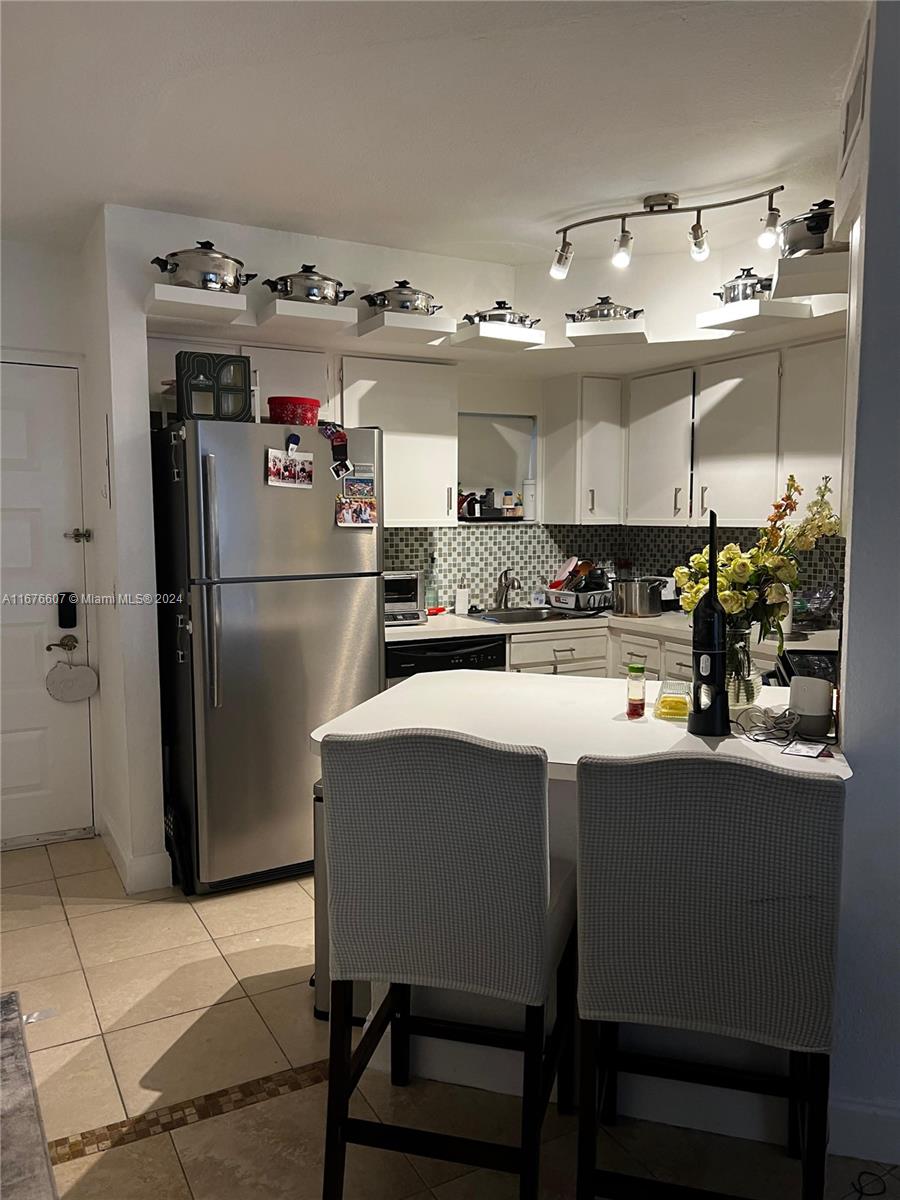 a kitchen with refrigerator and chairs