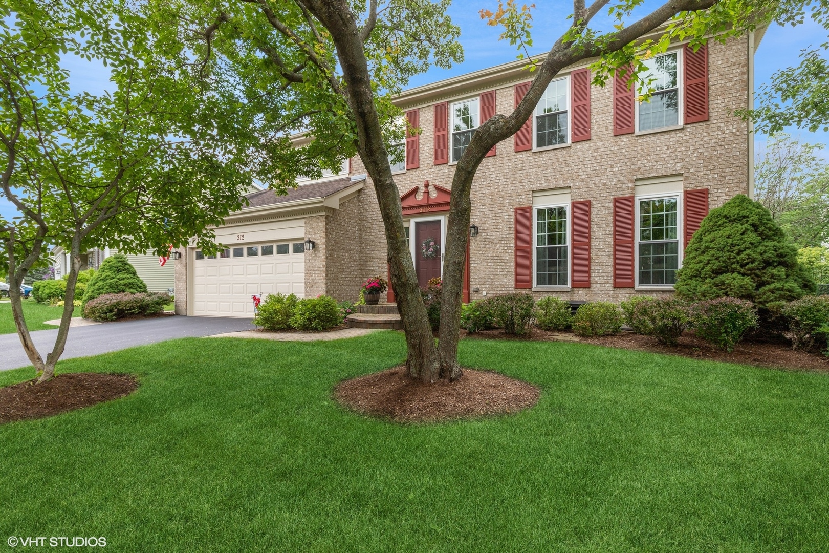 a front view of a house with a yard and garden