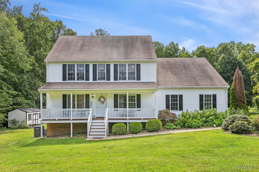 Colonial house with a storage unit, a porch, and a