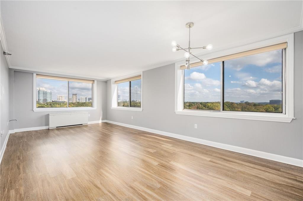 a view of an empty room with a window and wooden floor