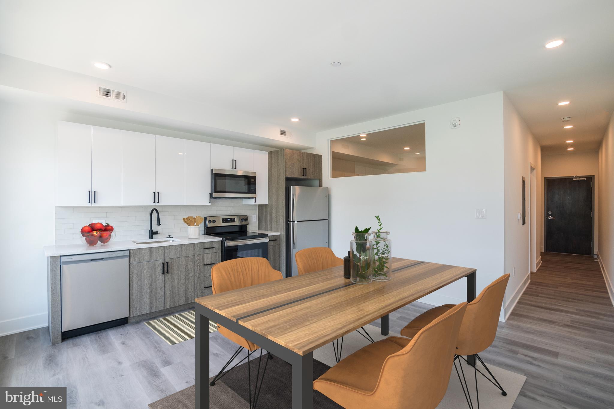 a kitchen with stainless steel appliances a dining table chairs and wooden floor