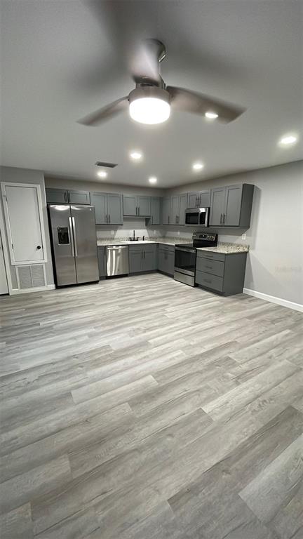 a large kitchen with stainless steel appliances kitchen island a large counter top a stove and a sink