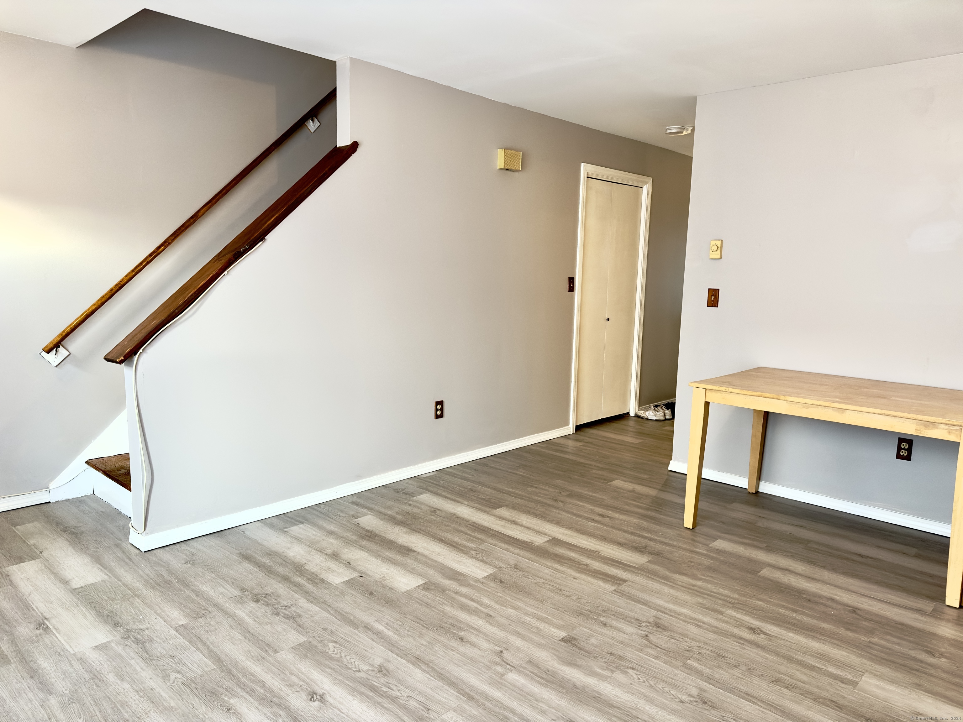 a view of an empty room with wooden floor and stairs