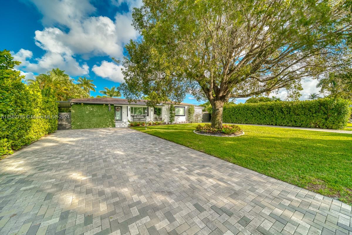 a view of a house with a big yard and large tree