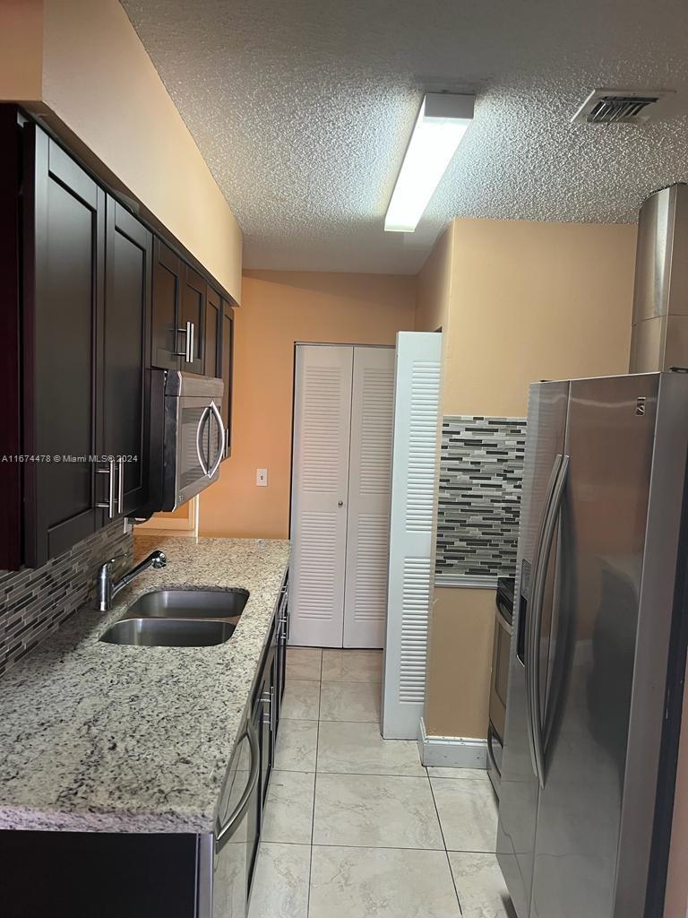 a kitchen with granite countertop a refrigerator and a sink