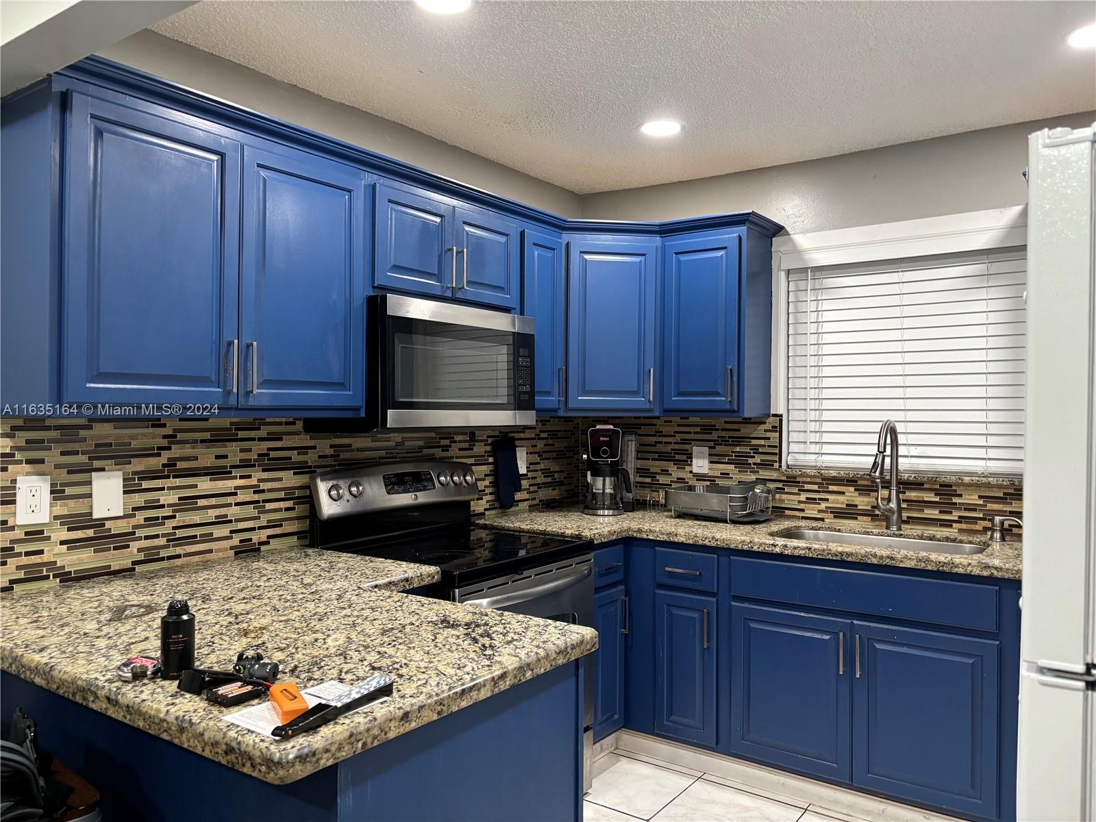 a kitchen with kitchen island granite countertop a sink stove and wooden cabinets