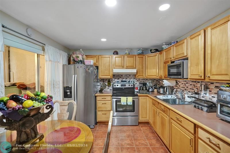 a kitchen with sink refrigerator and microwave