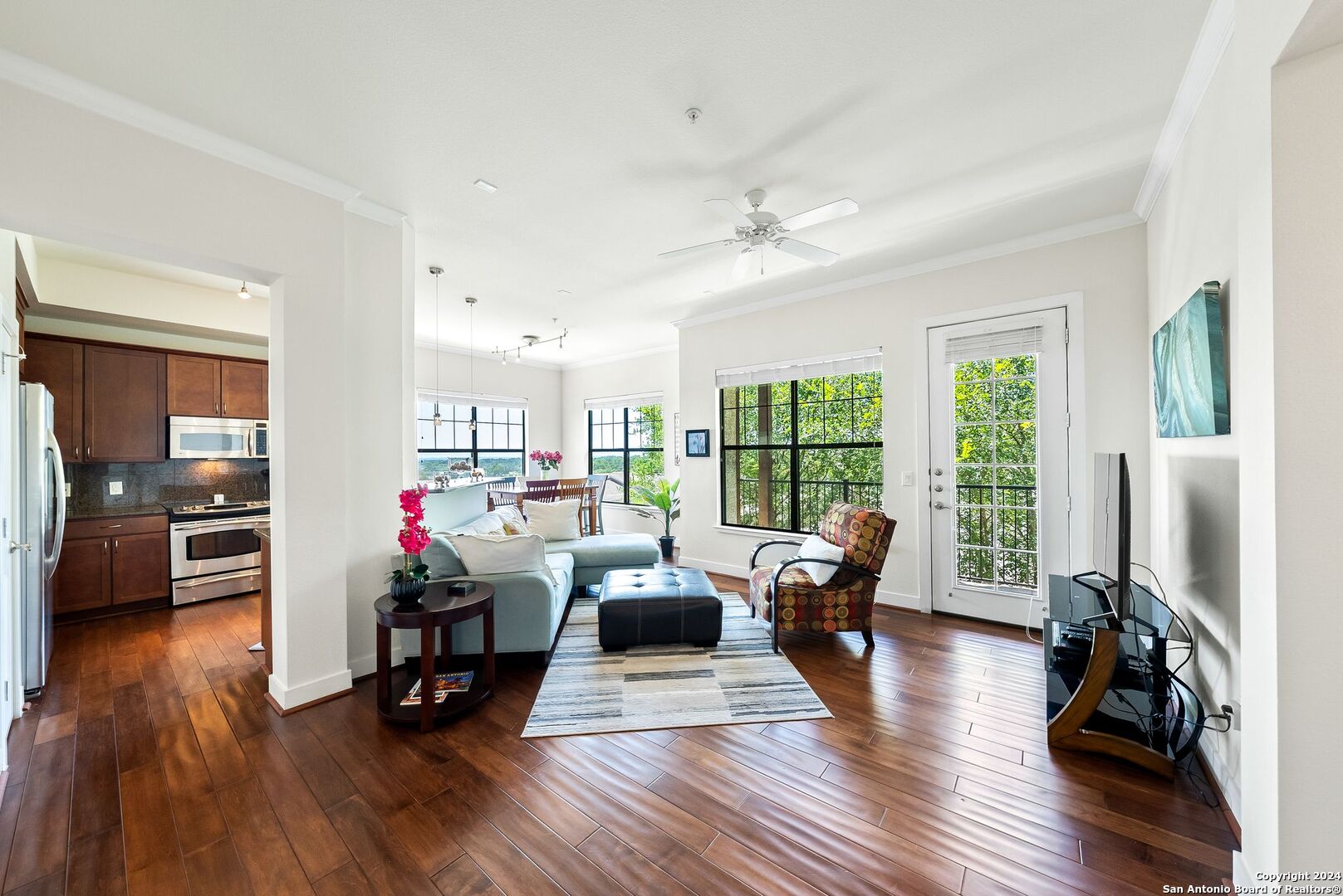 a living room with furniture large window and wooden floor