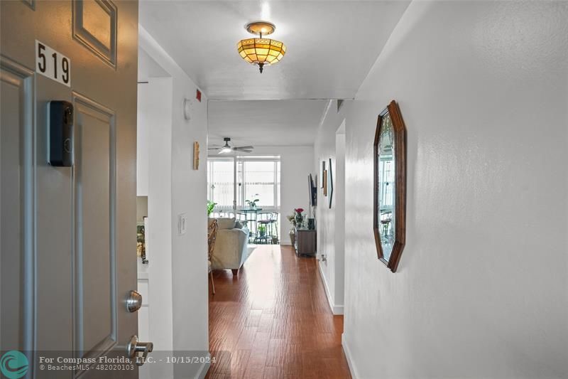 a view of a hallway with wooden floor and a living room