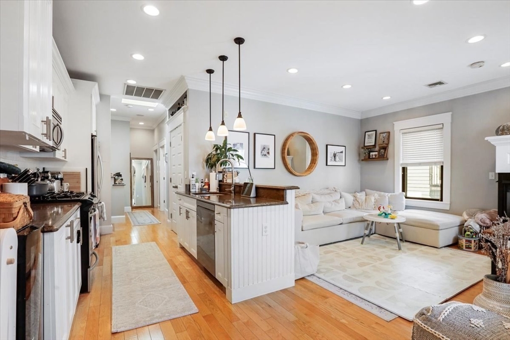 a living room with stainless steel appliances kitchen island granite countertop a stove and a view of living room