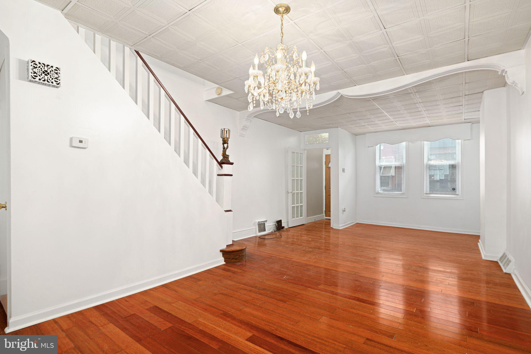 a view of an empty room with wooden floor and a chandelier