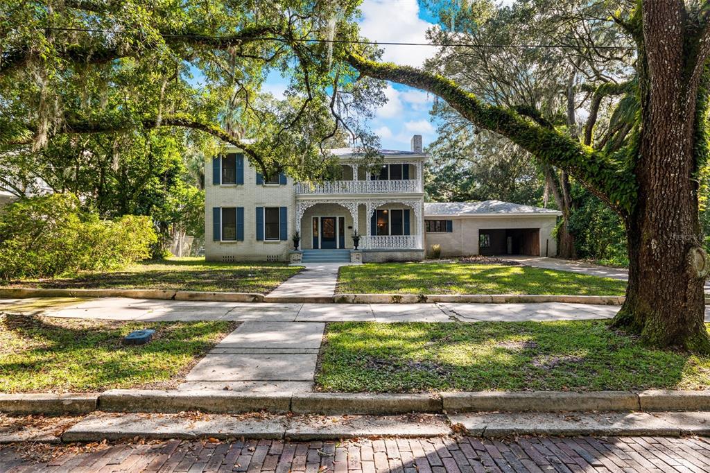 a front view of house with garden and trees