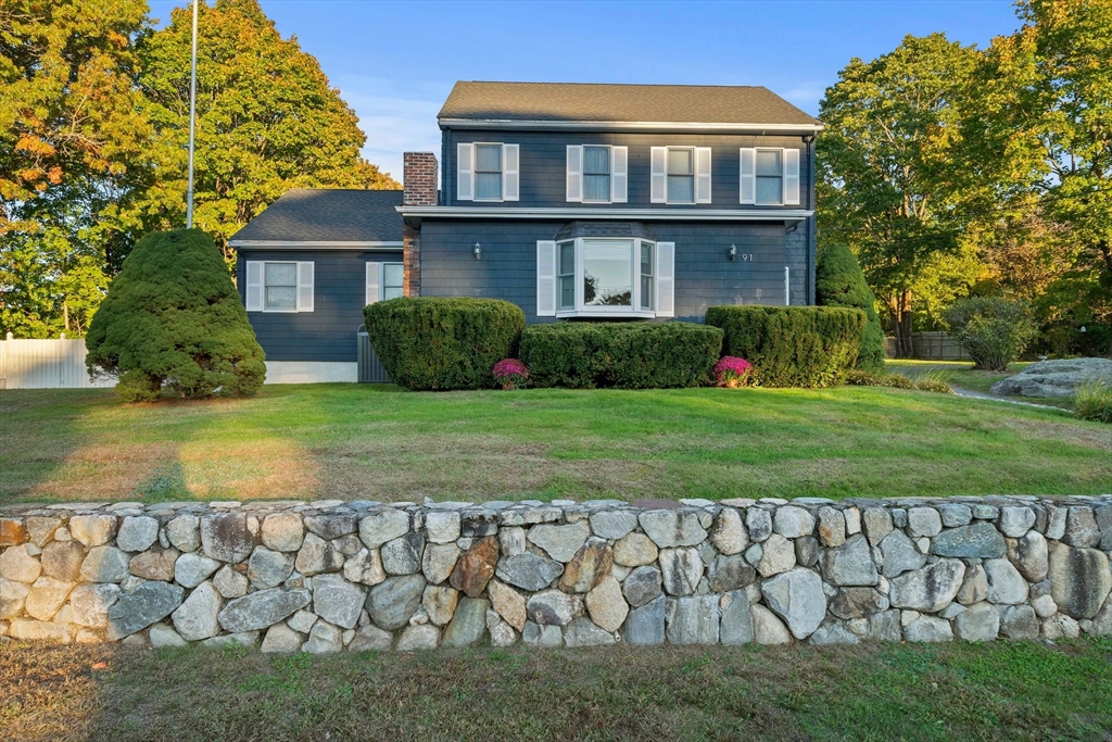 a view of a brick house next to a yard with large trees