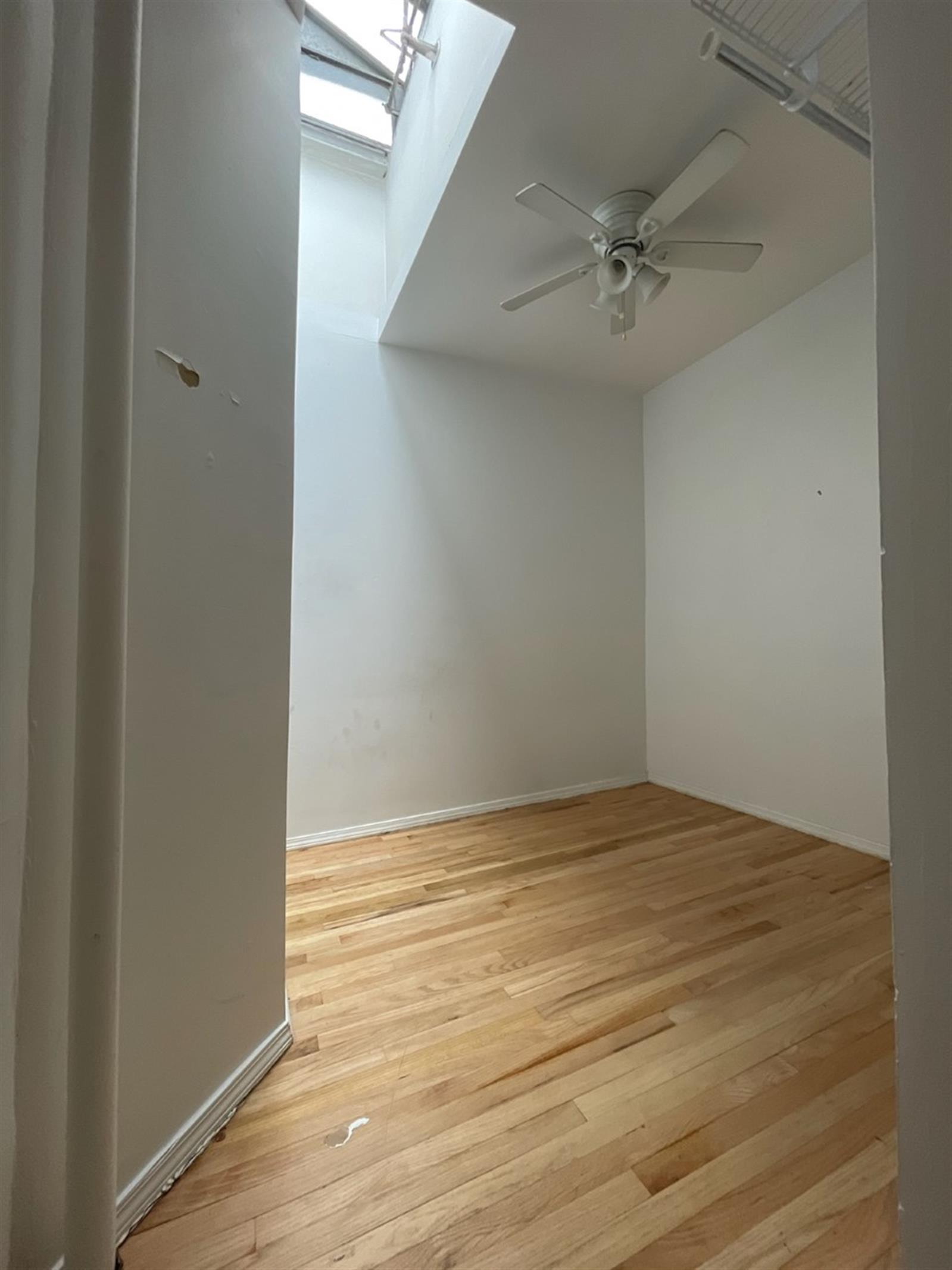 an empty room with wooden floor and fan