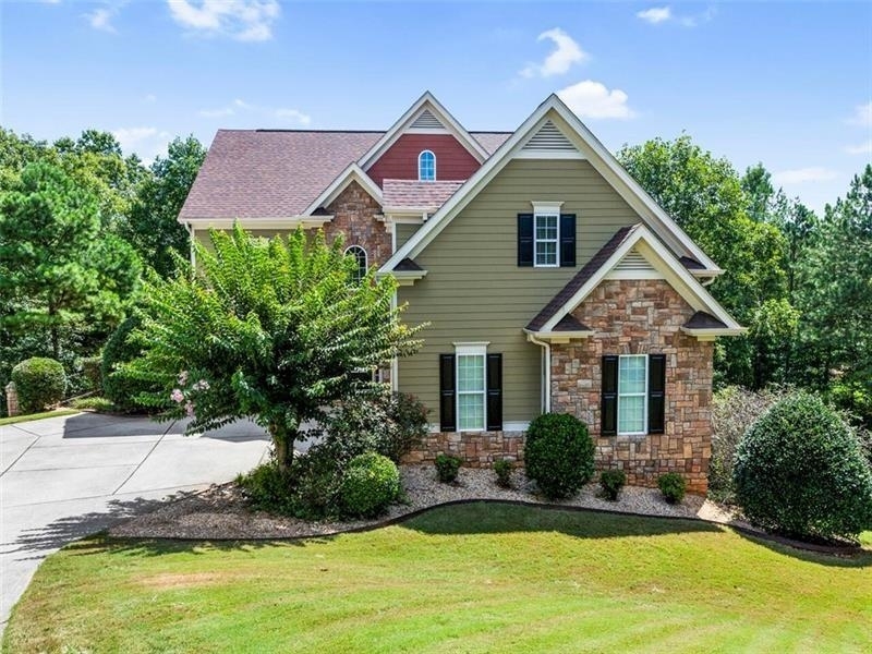 a front view of house with yard and trees in the background