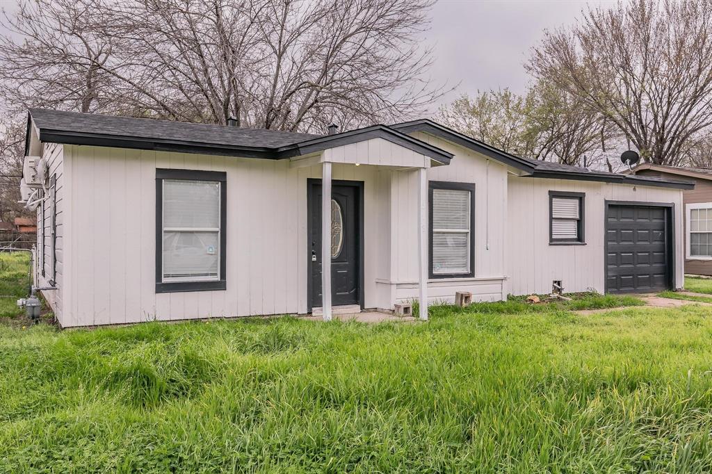 a front view of house with yard and trees in the background