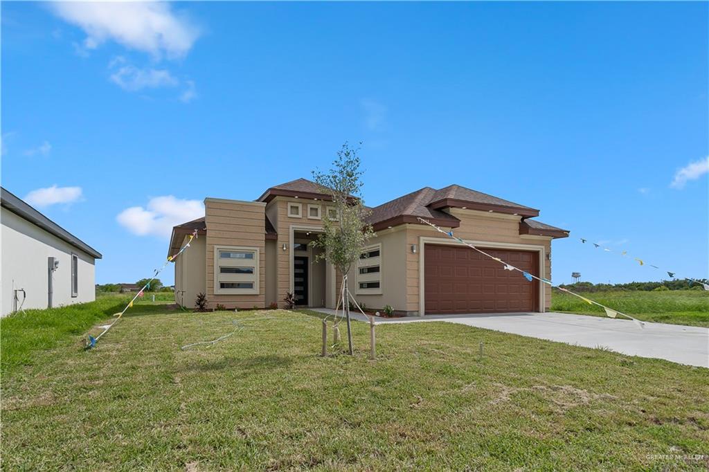 Prairie-style home featuring a garage and a front lawn