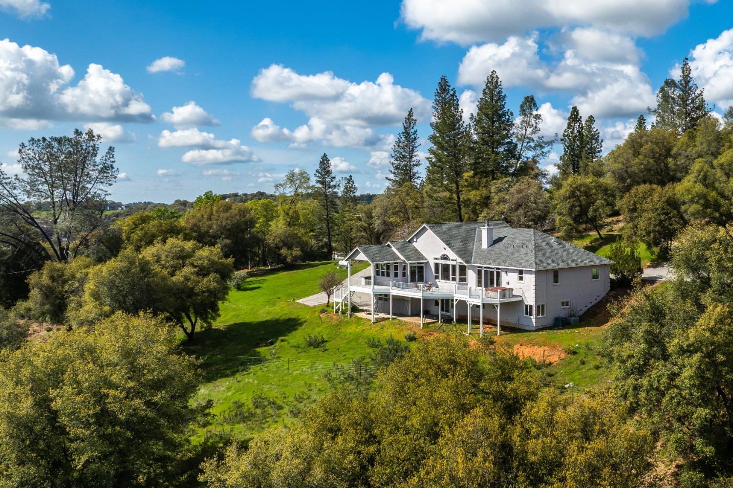 a view of a house with a big yard and large trees