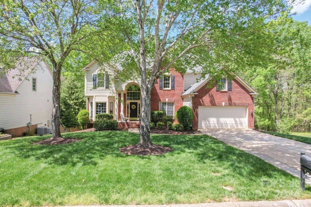 a front view of a house with a yard and large trees