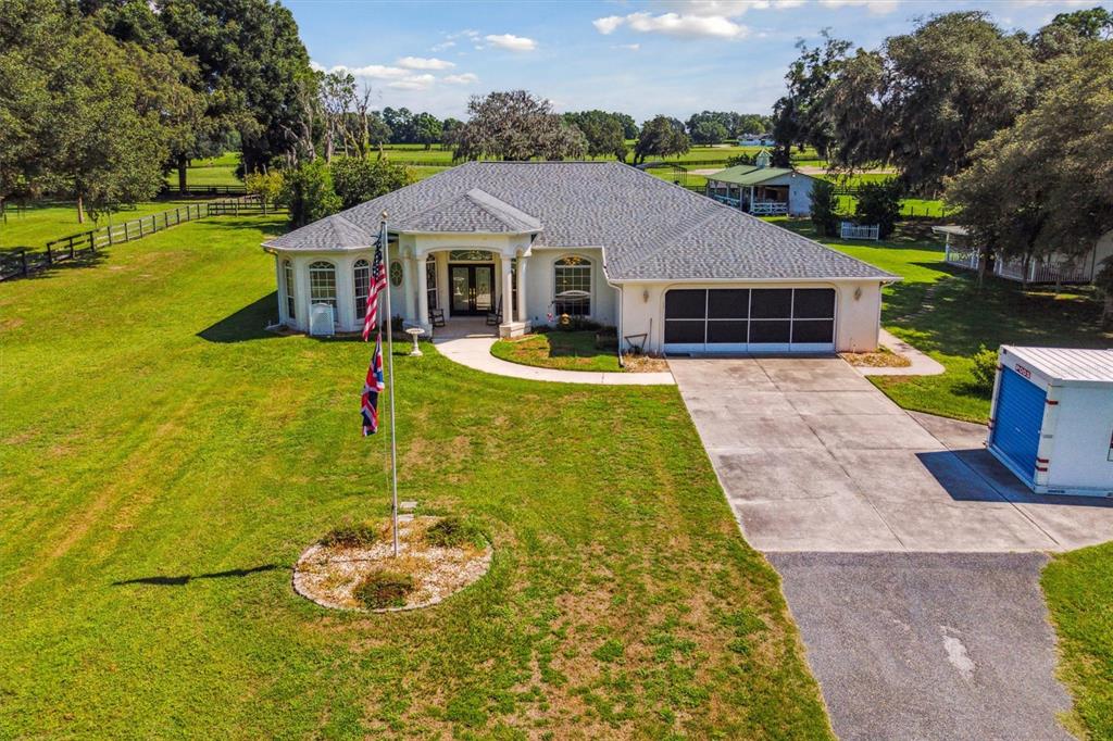 a aerial view of a house with swimming pool lawn chairs and a fire pit