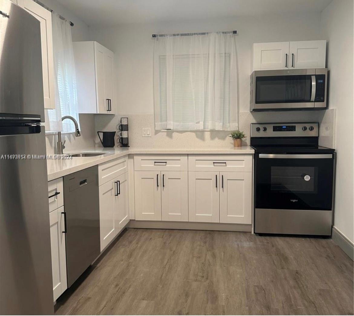 a kitchen with a sink white cabinets and stainless steel appliances