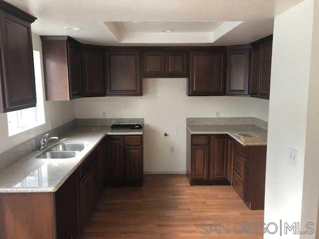 a kitchen with granite countertop wooden cabinets and a stove top oven