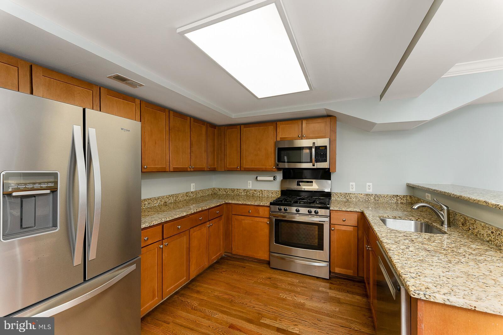 a kitchen with stainless steel appliances granite countertop a refrigerator a stove sink and microwave