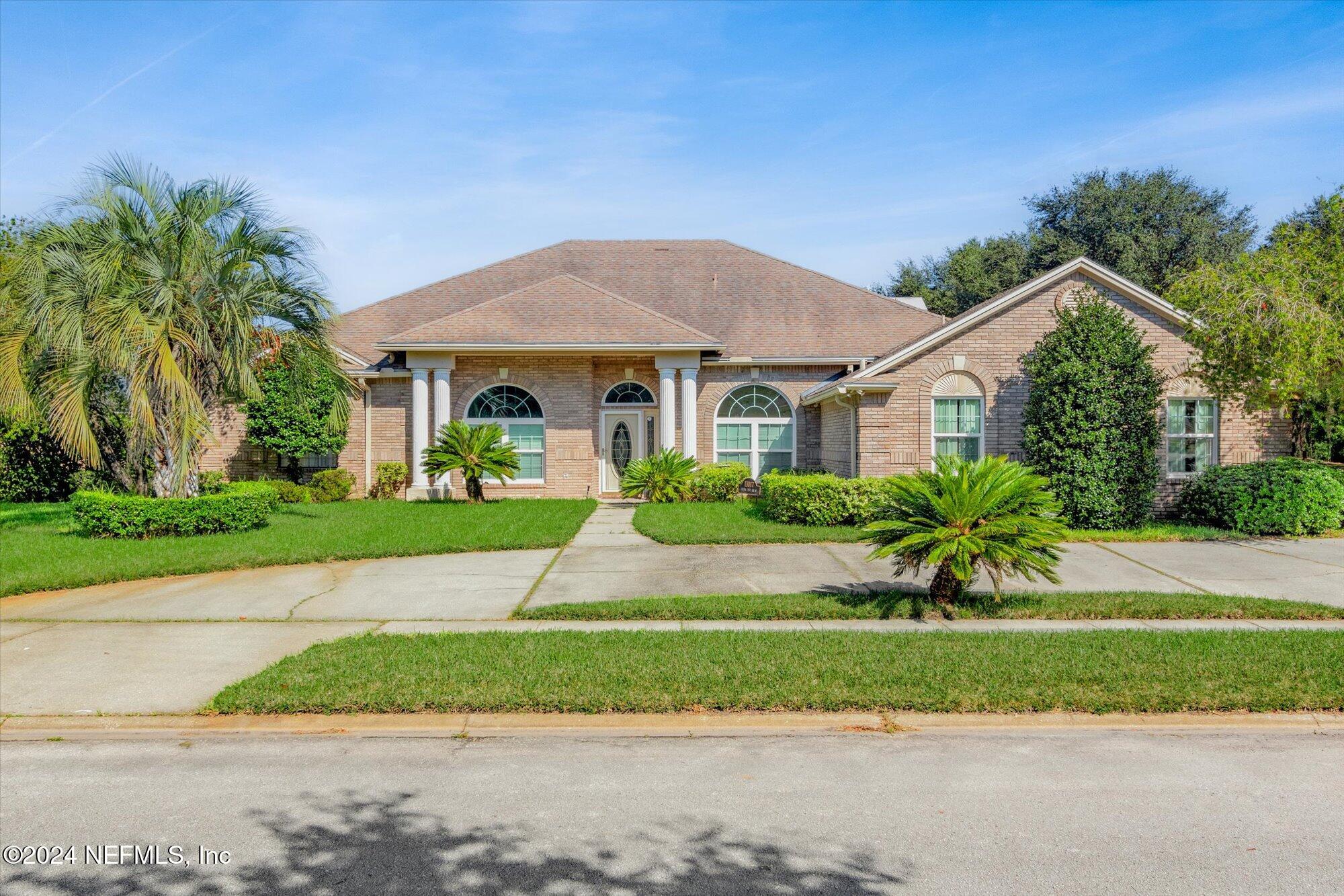 a front view of a house with a yard and potted plants