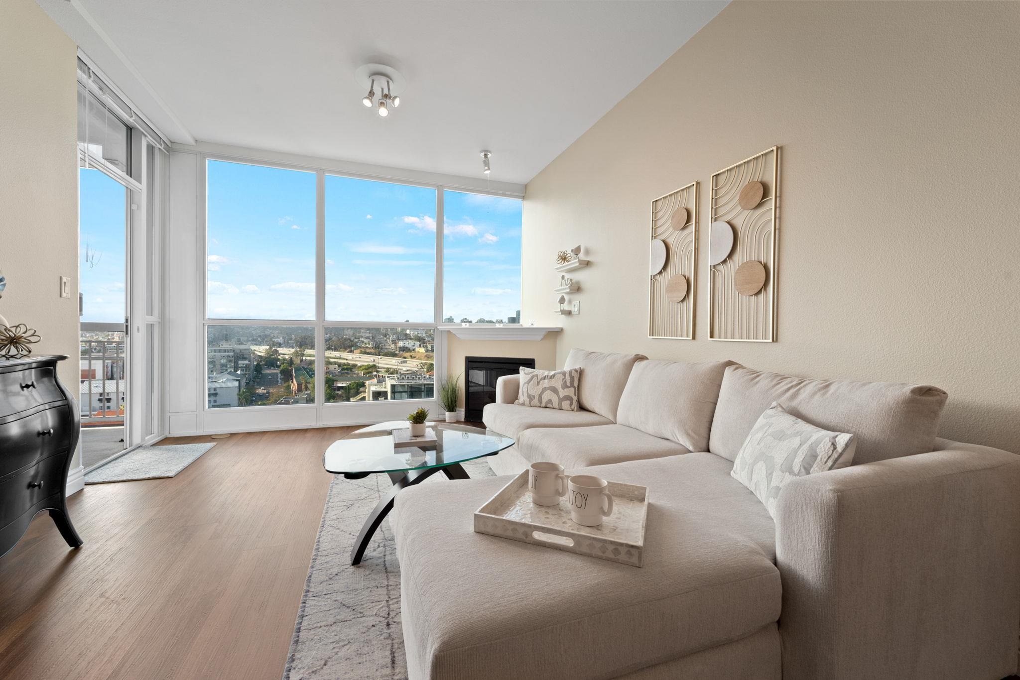 a living room with furniture large windows and wooden floor