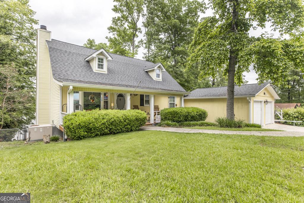 a view of a house next to a big yard and large trees