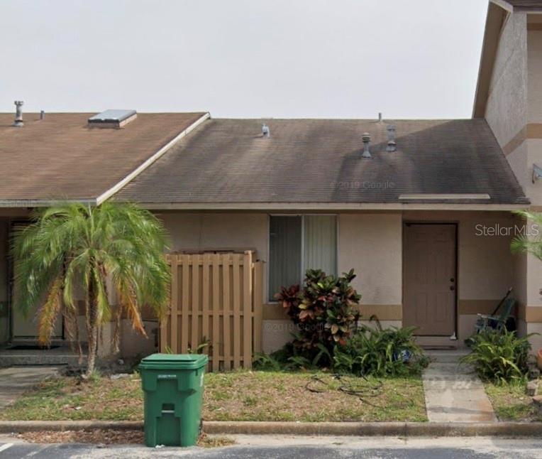 a backyard of a house with potted plants and palm tree