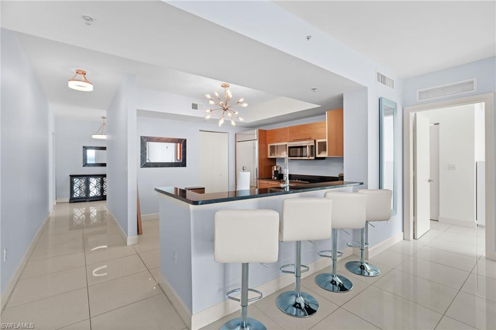 Kitchen with a notable chandelier, a breakfast bar, kitchen peninsula, and light tile patterned floors