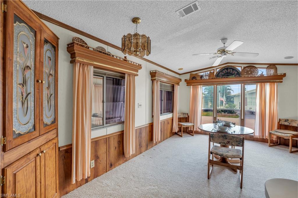 Carpeted dining room featuring ceiling fan, vaulted ceiling, and a textured ceiling