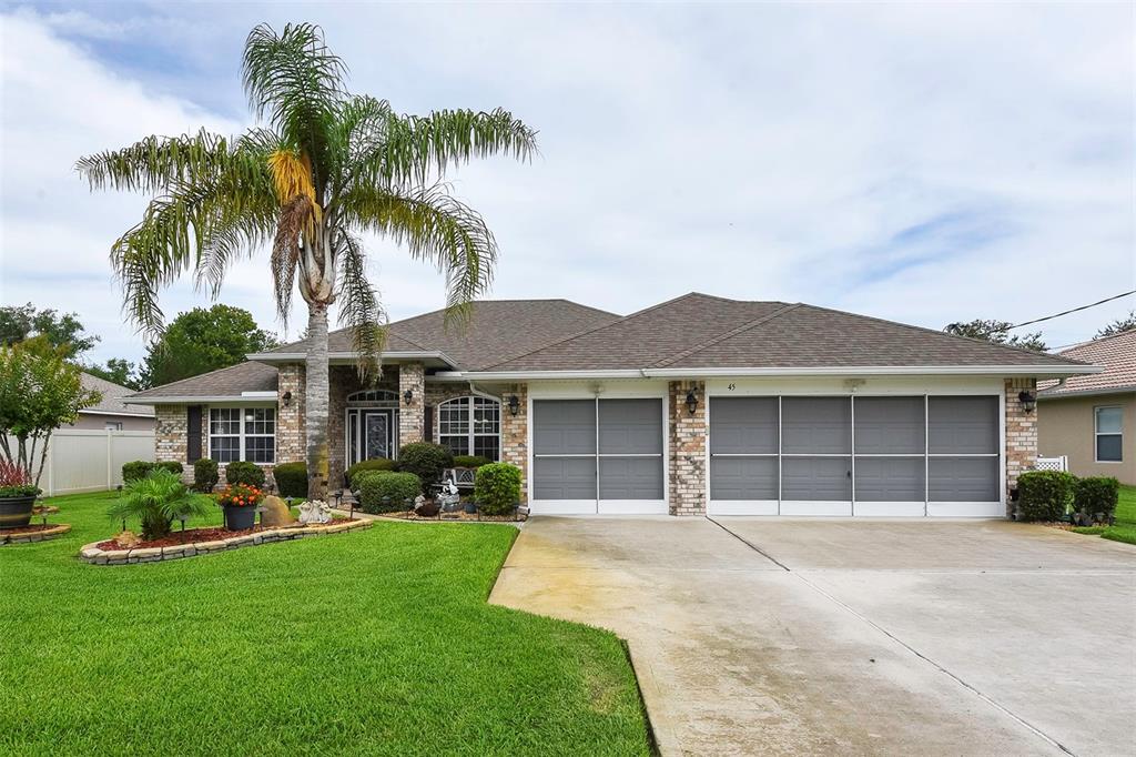 a front view of a house with a garden and palm tree