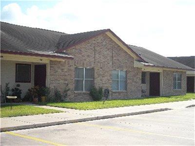 a brick house next to a yard and road