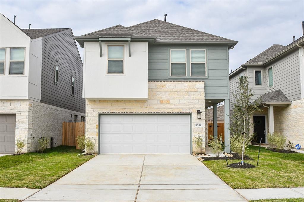 The front of the house presents a welcoming facade with a wide attached garage and a captivating blend of exterior finishes. The overall effect is a picture-perfect home that beautifully complements the greenery of the surroundings.