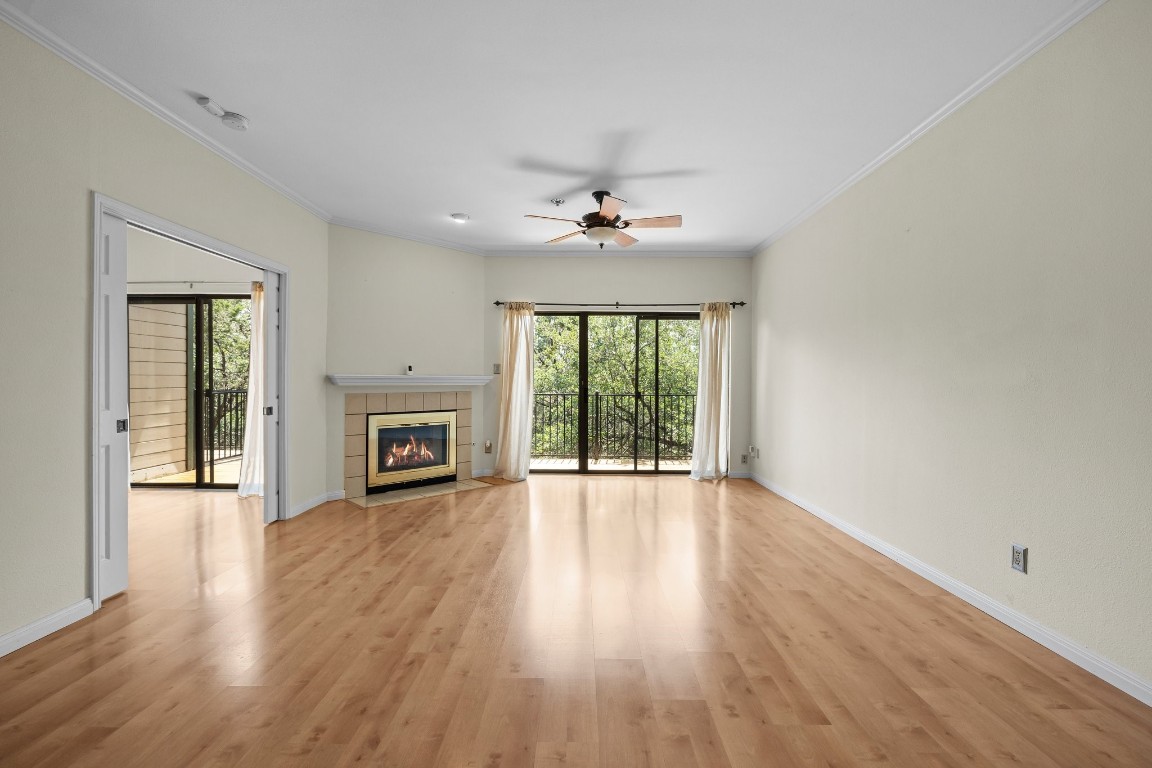 an empty room with wooden floor fireplace and windows