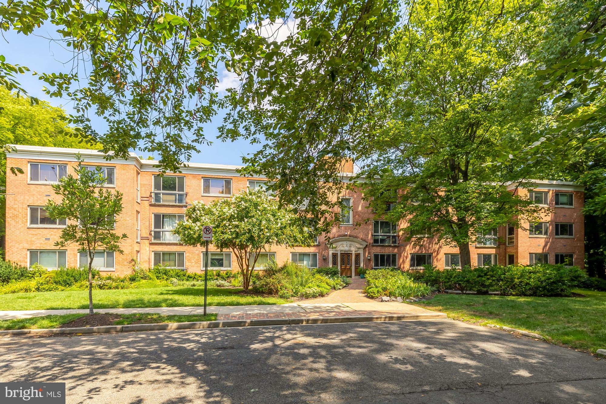 a view of a brick house next to a yard with big trees