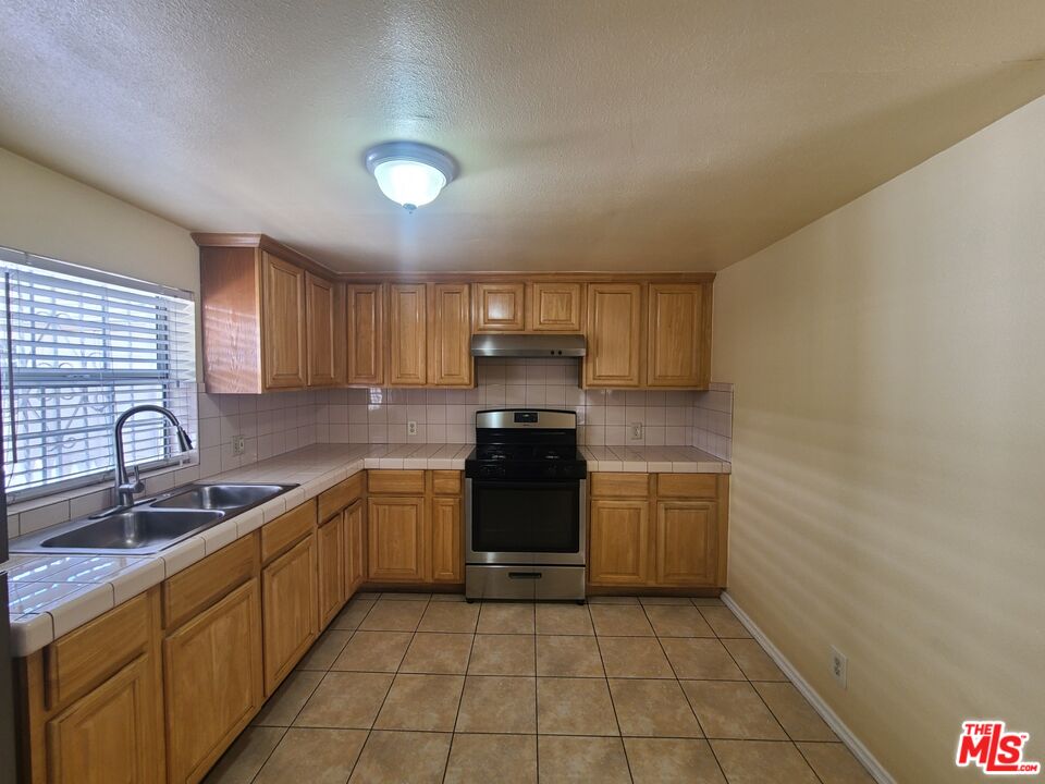 a kitchen with granite countertop a stove a sink and a microwave