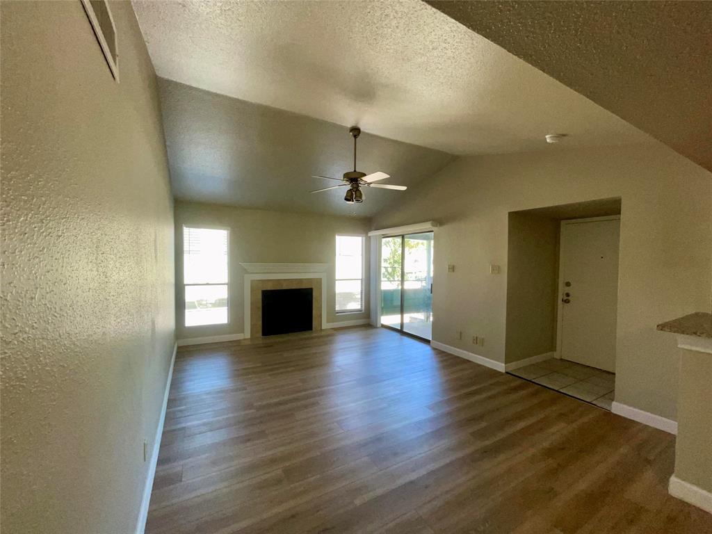 a view of empty room with wooden floor and fireplace