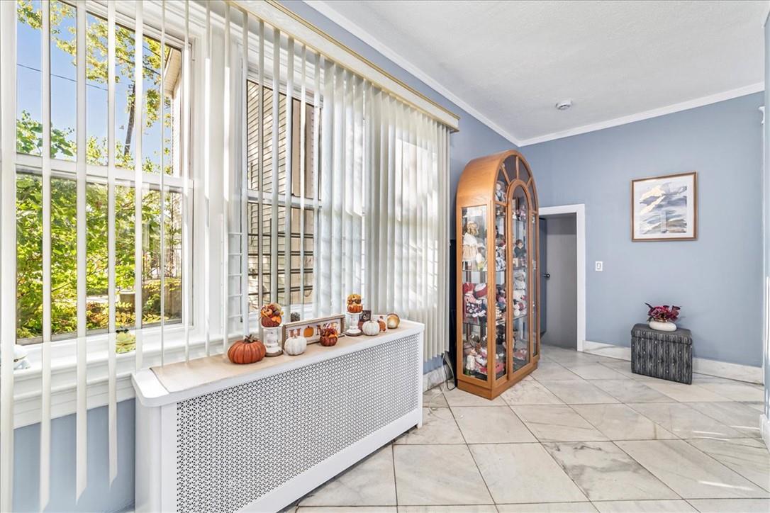 Corridor featuring light tile patterned flooring, crown molding, and radiator