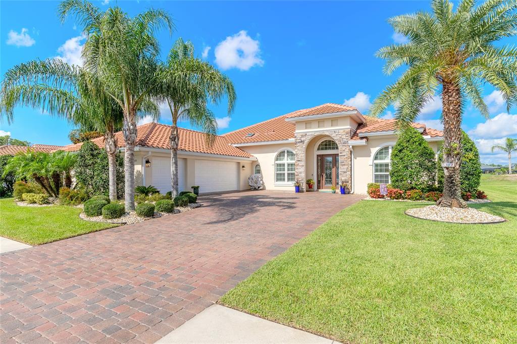 a front view of a house with a garden and palm trees