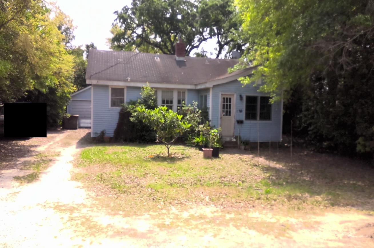 a front view of house with yard and trees in the background